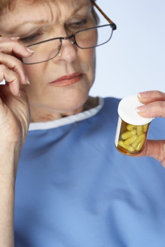 An image shows a woman is holding some medicine and discussing something on the phone.
